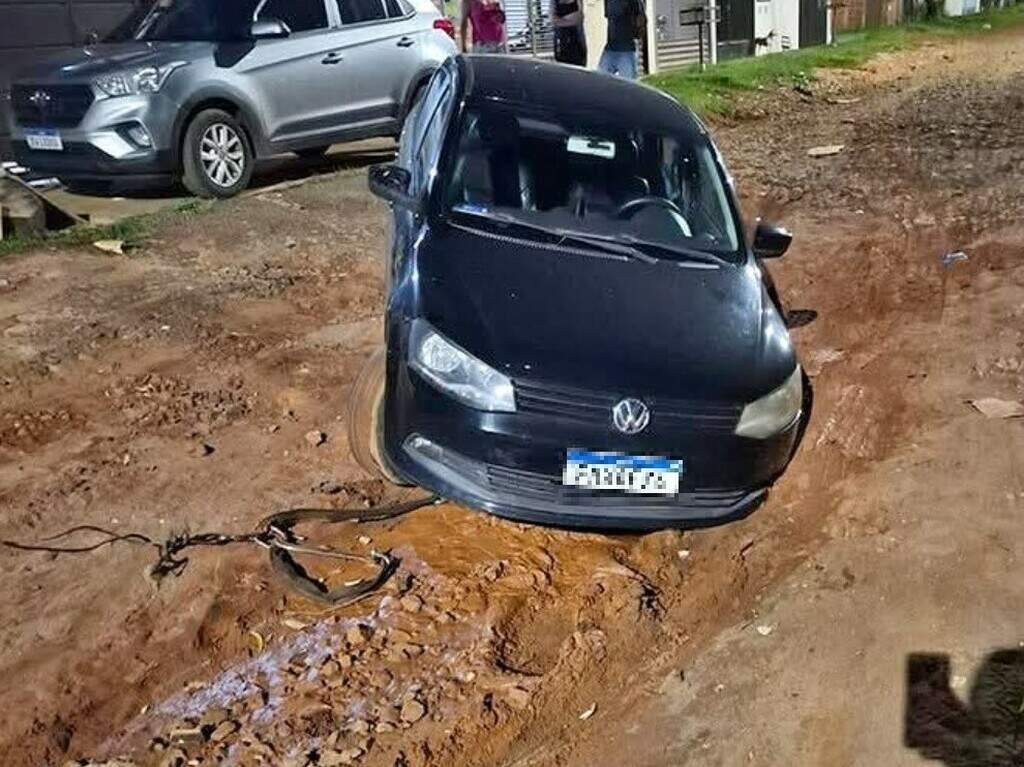 Cratera que atolou caminhão de lixo agora deixa Voyage preso em rua